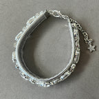 A silver-toned cat collar embellished with clear faceted rhinestones, featuring a lobster clasp, extension chain, and dangling star charm, displayed on a textured gray fabric background.