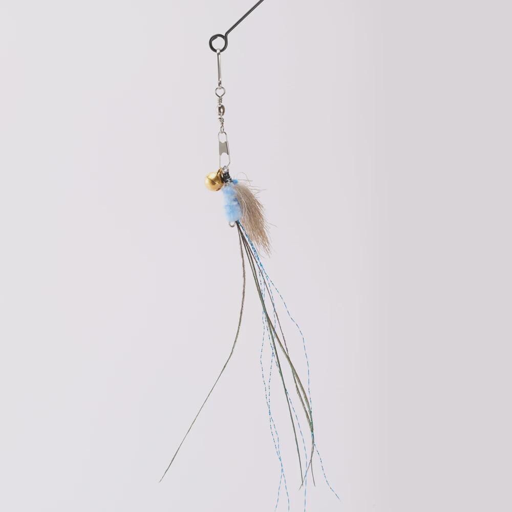 A cat toy with a small gold bell, a light blue bead, a beige feather, and long dangling strands in olive green and light blue, suspended against a plain light gray background.