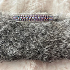 A silver-toned double-row cuff bracelet with iridescent purple and blue rhinestones, displayed on a gray faux fur surface against a white faux fur background.