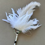 A white feather duster with a white beaded handle and black accents, photographed on a neutral gray background.