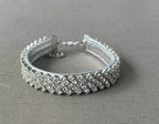 A silver-toned collar encrusted with clear rhinestones, displayed on a textured gray fabric background.
